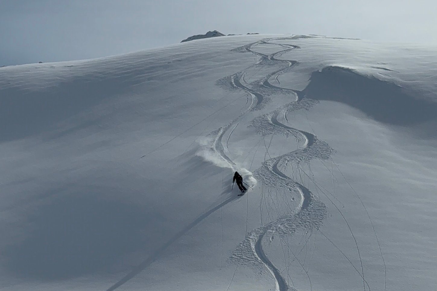 Skieur dans la neige fraîche sur un vaste versant à Val d’Isère, avec ses traces derrière lui
