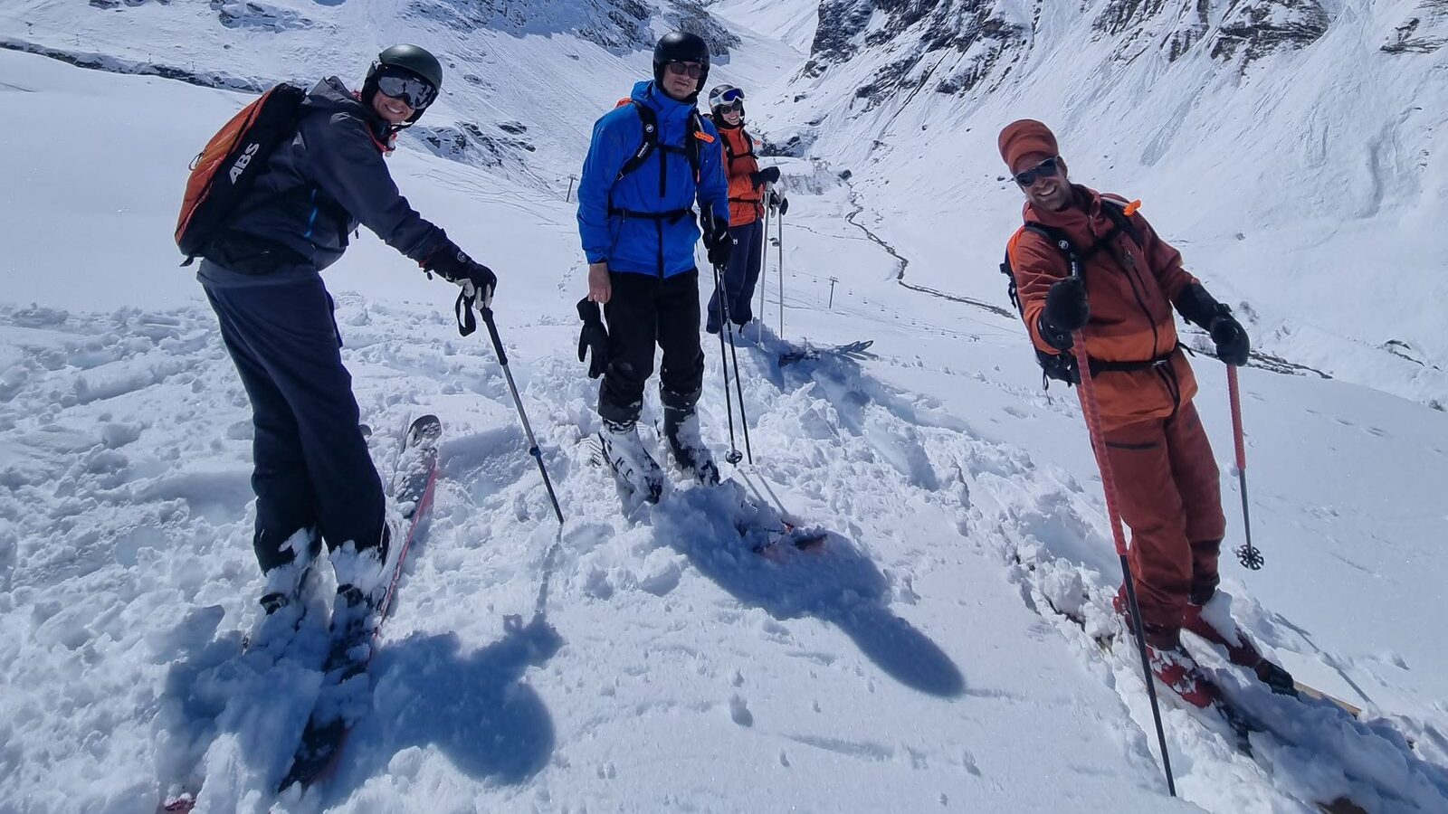 Un moniteur et trois skieurs en hors-piste sur le domaine Val d’Isère–Tignes, avec une remontée mécanique en contrebas