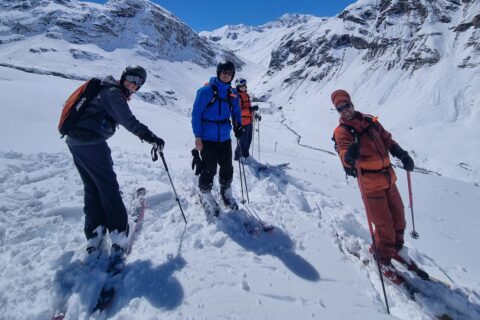 Un moniteur et trois skieurs en hors-piste sur le domaine Val d’Isère–Tignes, avec une remontée mécanique en contrebas